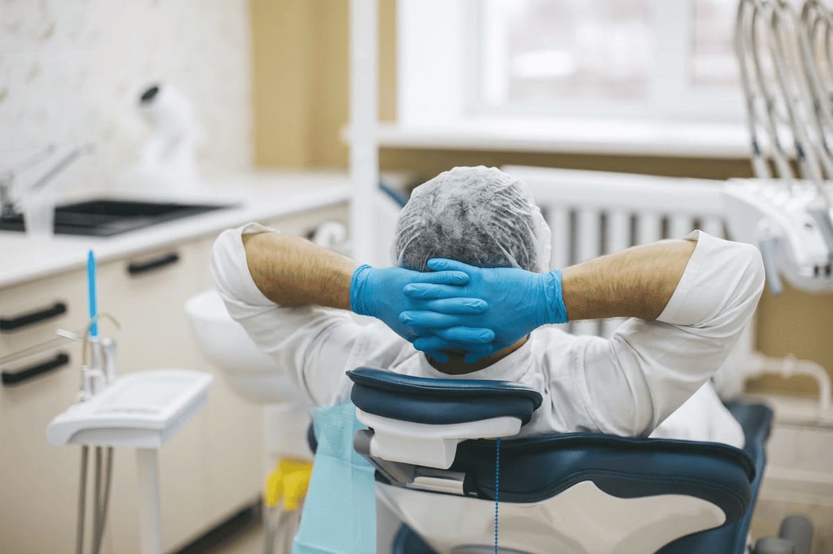 Un dentista sdraiato in poltrona che, sfinito, si riposa: la crisi delle ASO nello studio può portare a un dentista stressato e un team con sintomi da burnout